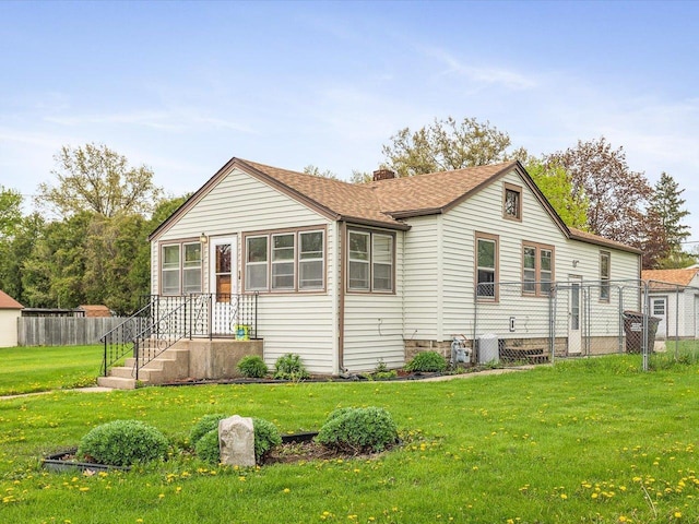 view of front facade with a chimney, a shingled roof, a front lawn, and fence