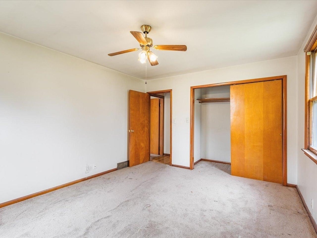 unfurnished bedroom with a closet, light carpet, and baseboards