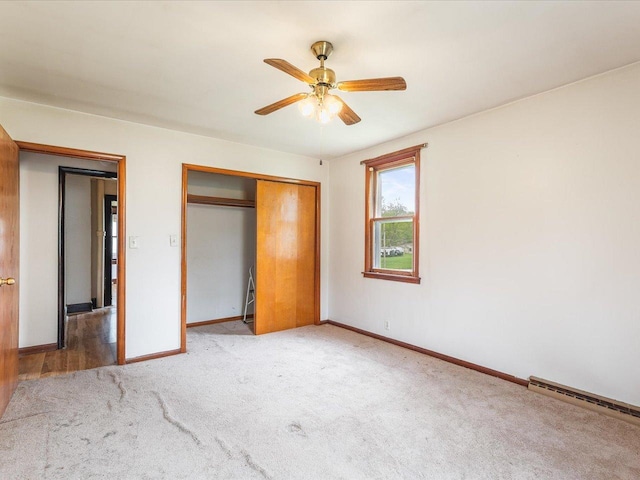 unfurnished bedroom featuring a closet, ceiling fan, carpet floors, baseboard heating, and baseboards