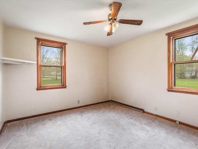 carpeted spare room featuring baseboards, a wealth of natural light, and a baseboard radiator