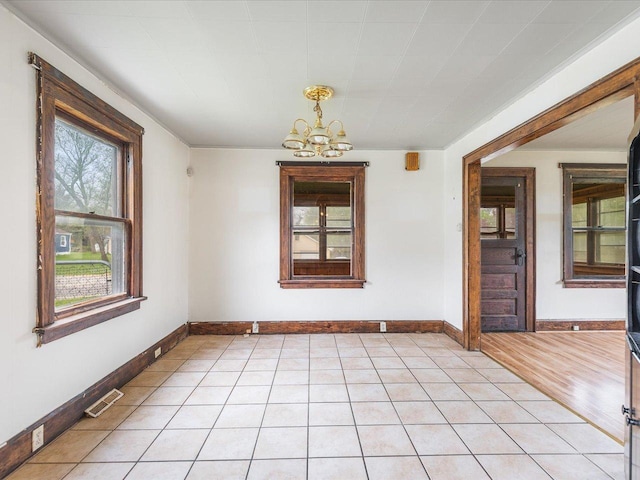 unfurnished room with a chandelier, baseboards, and visible vents