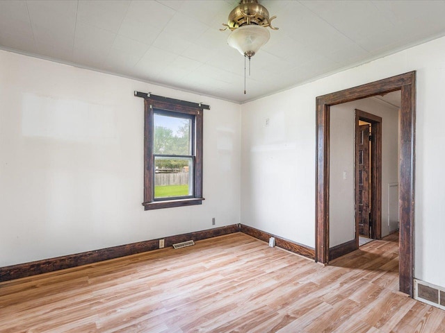 empty room with light wood-style flooring, baseboards, and visible vents