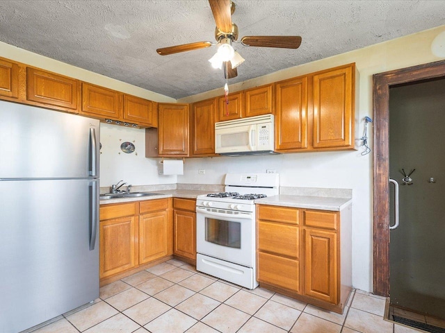 kitchen featuring brown cabinets, a sink, ceiling fan, white appliances, and light countertops