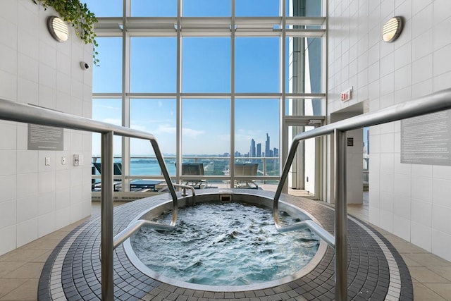 interior space with tile walls, expansive windows, a high ceiling, a water view, and a view of skyline
