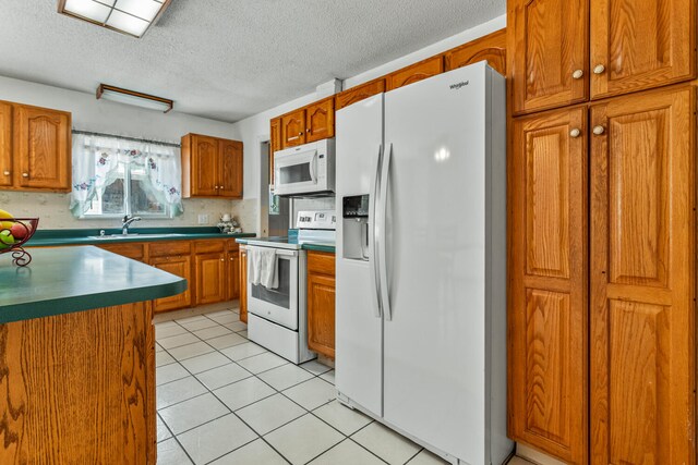 2503 Maplewood Dr, Champaign, IL 61821 - kitchen with white appliances, a sink, brown cabinets, a textured ceiling, and light tile patterned flooring