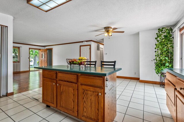 2503 Maplewood Dr, Champaign, IL 61821 - kitchen featuring dark countertops, ceiling fan, light tile patterned flooring, a textured ceiling, and a center island