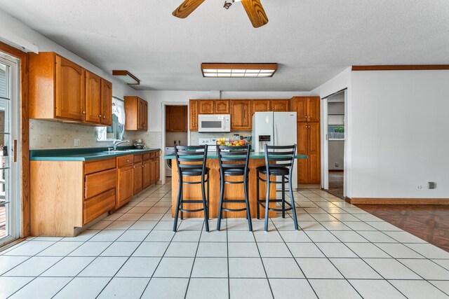 2503 Maplewood Dr, Champaign, IL 61821 - kitchen featuring white appliances, a sink, ceiling fan, brown cabinetry, and a breakfast bar area