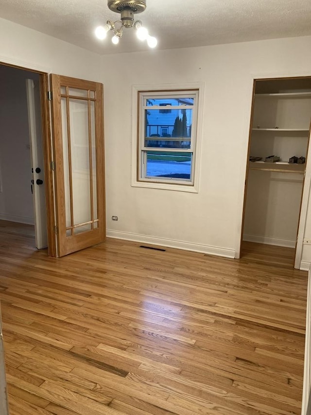 303 N School St, Mount Prospect, IL 60056 - unfurnished bedroom featuring light wood-style flooring, a closet, a textured ceiling, baseboards, and a chandelier