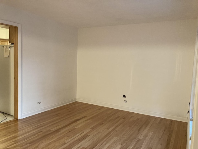 spare room featuring baseboards and wood finished floors