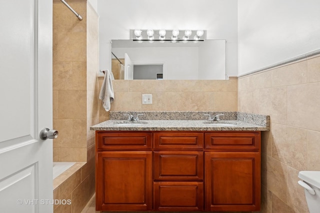 full bathroom featuring tile walls, double vanity, toilet, and tiled shower / bath