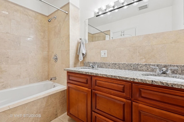 bathroom with tiled shower / bath combo, tile walls, double vanity, and tile patterned floors