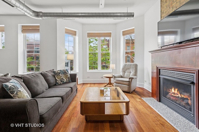 living room featuring wood finished floors, a fireplace with flush hearth, and baseboards