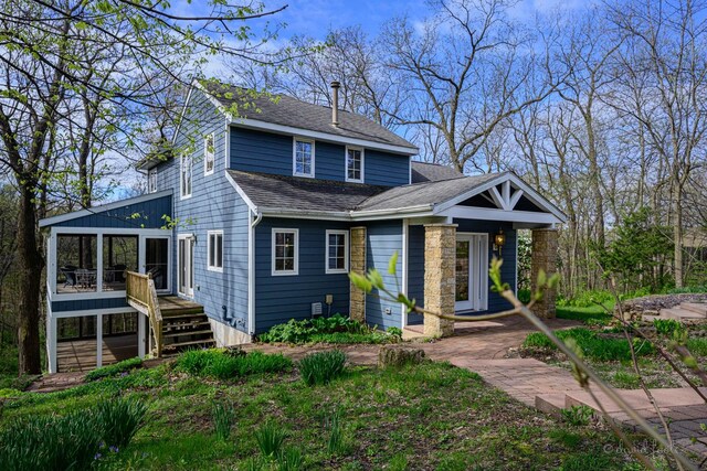 view of front of house featuring roof with shingles and a sunroom