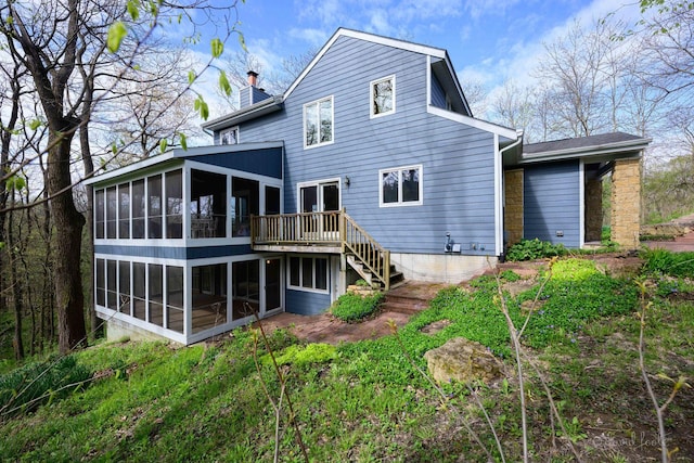 rear view of house with a sunroom, a chimney, a wooden deck, and stairway