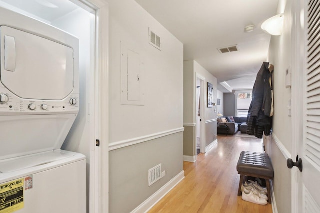 laundry area with estacked washer and dryer, light wood-style floors, and baseboards