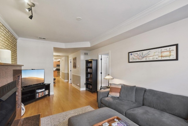 living area featuring wood finished floors, crown molding, and baseboards
