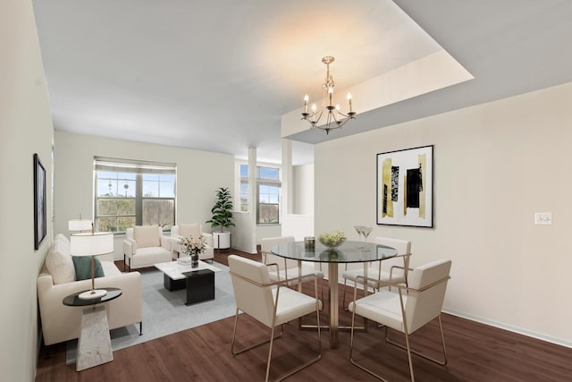 dining area with baseboards, a notable chandelier, and wood finished floors