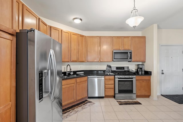 kitchen with hanging light fixtures, light tile patterned flooring, a sink, dark countertops, and stainless steel appliances