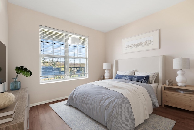 bedroom with wood finished floors, baseboards, and multiple windows