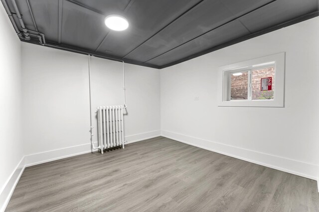 7732 W Sunset Dr, Elmwood Park, IL 60707 - empty room with wood finished floors, baseboards, and radiator heating unit