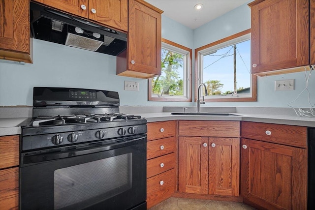 kitchen featuring gas stove, extractor fan, a sink, and brown cabinets