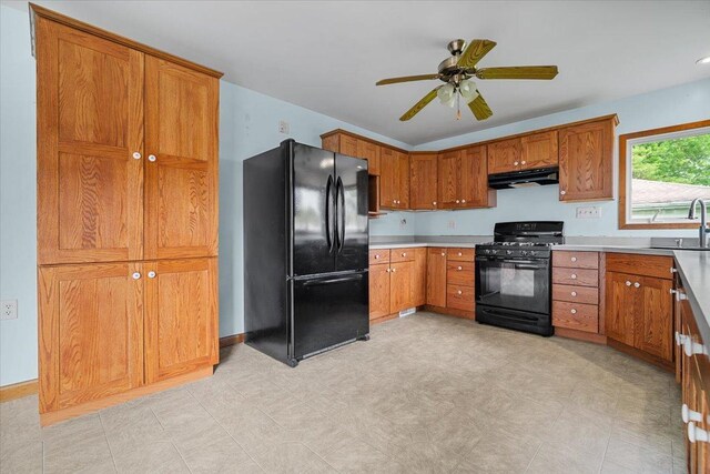 kitchen featuring black appliances, under cabinet range hood, brown cabinets, and a ceiling fan