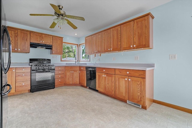 kitchen with black appliances, under cabinet range hood, brown cabinetry, and light countertops