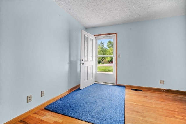 foyer with wood finished floors, a textured ceiling, and baseboards
