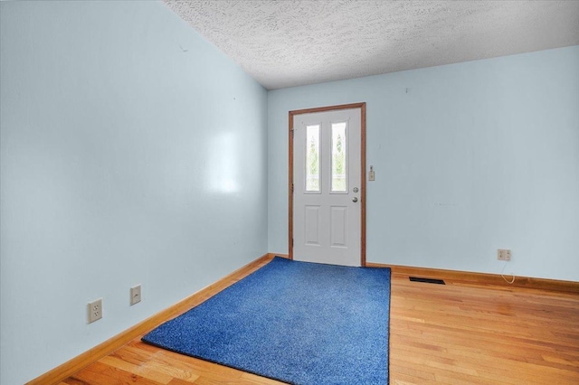 foyer entrance with wood finished floors, baseboards, and a textured ceiling