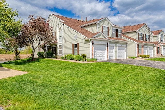 view of property featuring an attached garage, driveway, a front lawn, and roof with shingles