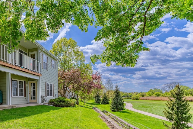 view of grassy yard featuring a balcony