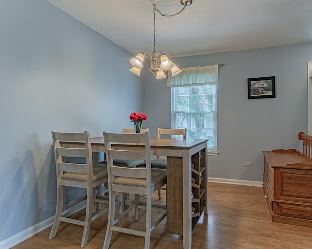 dining space featuring a chandelier, wood finished floors, and baseboards