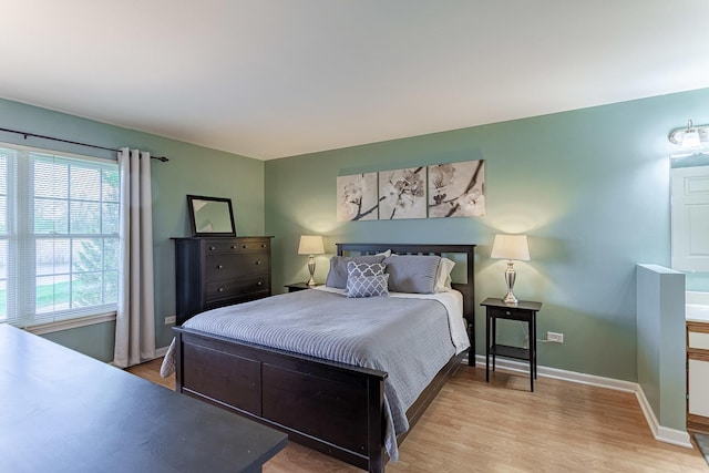 bedroom with multiple windows, light wood-style flooring, and baseboards