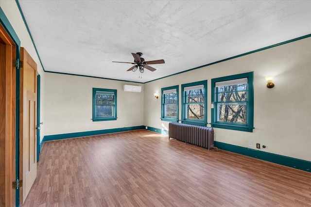 305 W Oregon St, Urbana, IL 61801 - unfurnished room featuring a ceiling fan, a wall mounted air conditioner, baseboards, radiator heating unit, and wood finished floors