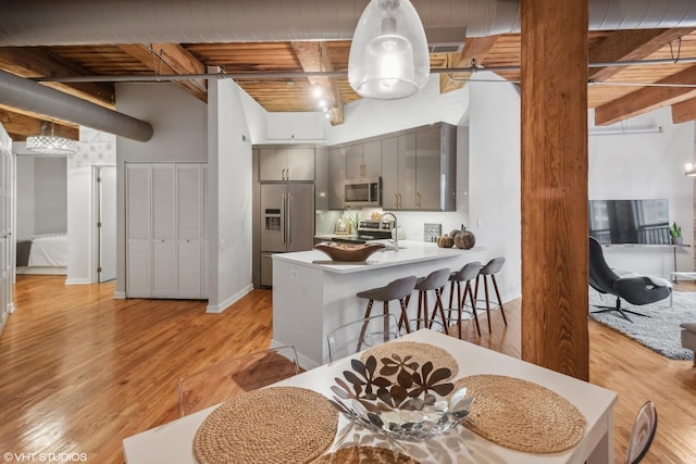 225 W Huron St Unit 507, Chicago, IL 60654 - kitchen with a peninsula, light wood finished floors, beam ceiling, gray cabinetry, and appliances with stainless steel finishes