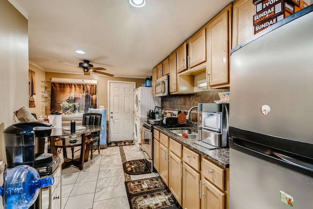 kitchen featuring a sink, dark stone counters, ceiling fan, appliances with stainless steel finishes, and tasteful backsplash