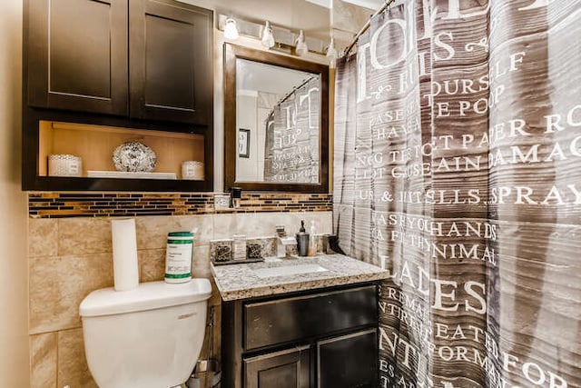 bathroom featuring vanity, toilet, and tile walls