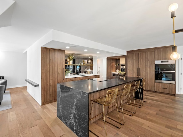 indoor wet bar with light wood-style flooring, black electric stovetop, stainless steel double oven, baseboards, and recessed lighting
