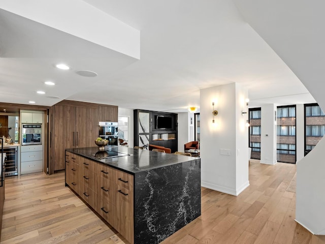 kitchen featuring beverage cooler, light wood-style flooring, a center island, modern cabinets, and recessed lighting
