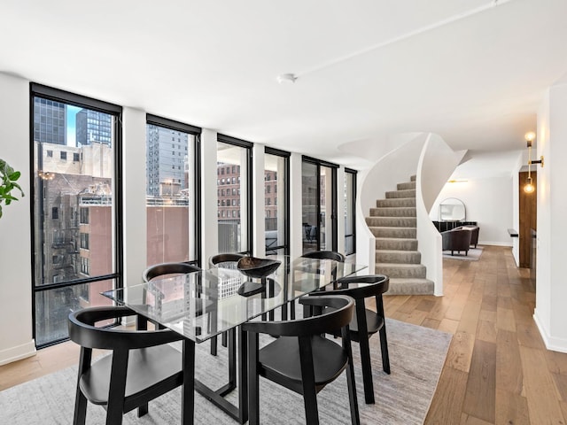 dining space with light wood-style flooring, baseboards, and stairs