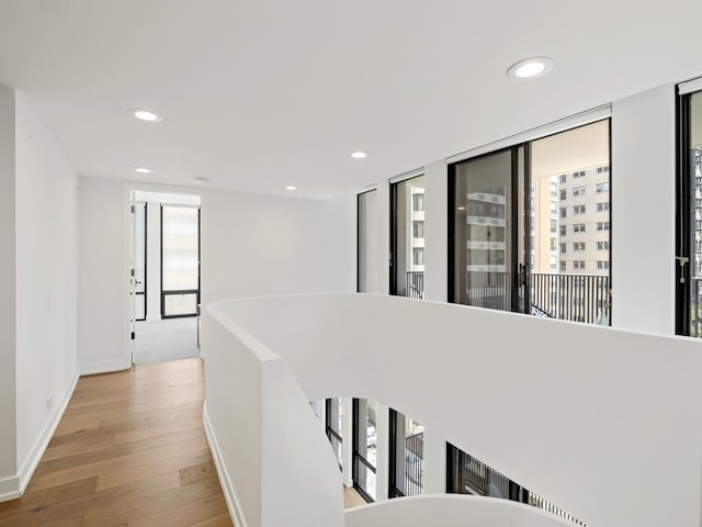 hall featuring wood-type flooring, plenty of natural light, recessed lighting, and baseboards
