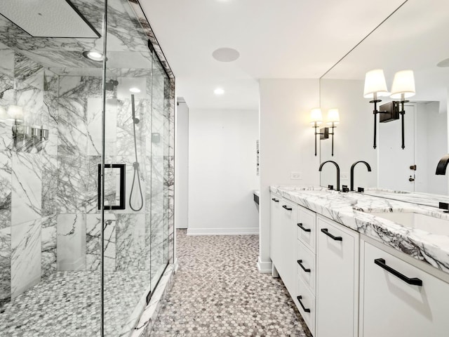 full bath featuring baseboards, a marble finish shower, double vanity, and recessed lighting