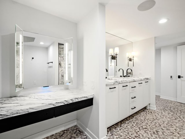 full bath featuring double vanity, recessed lighting, baseboards, and a chandelier