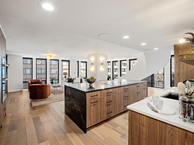 kitchen featuring modern cabinets, open floor plan, light wood-type flooring, a sink, and recessed lighting