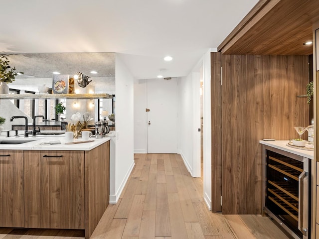 indoor bar with beverage cooler, light wood-type flooring, baseboards, and recessed lighting