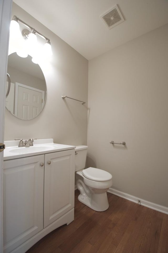 bathroom featuring toilet, vanity, visible vents, and wood finished floors