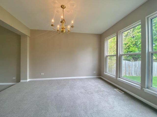 spare room with baseboards, an inviting chandelier, visible vents, and carpet floors