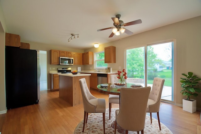 dining space with a ceiling fan, baseboards, and light wood-style flooring
