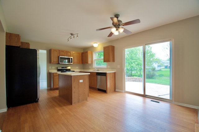 kitchen with visible vents, light wood finished floors, light countertops, a kitchen island, and appliances with stainless steel finishes