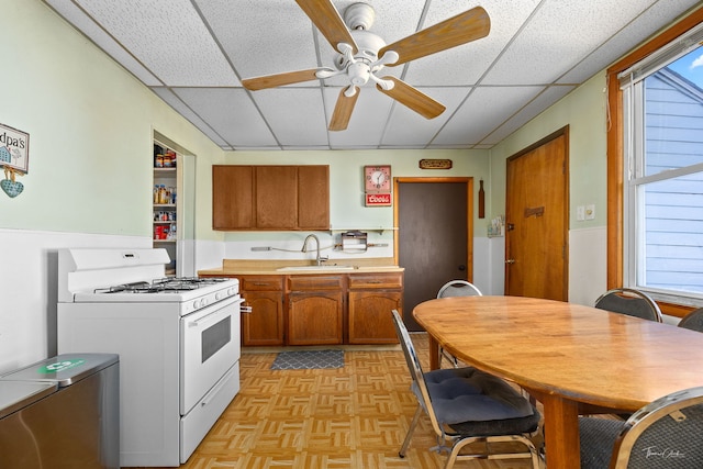 2862 S Keeley St, Chicago, IL 60608 - kitchen with a sink, brown cabinetry, gas range gas stove, ceiling fan, and light countertops